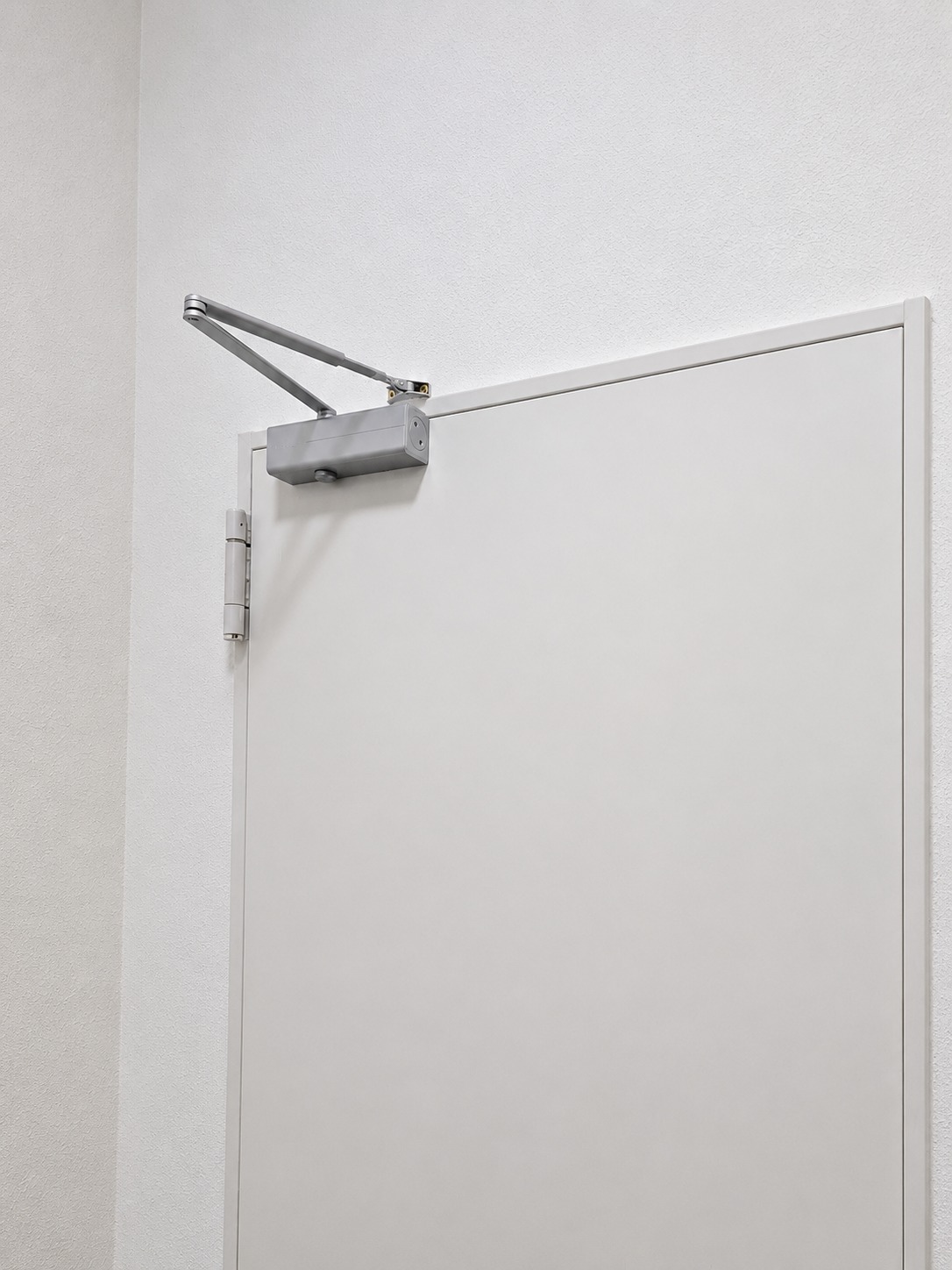 Cierrapuertas de brazo articulado instalado sobre una puerta
